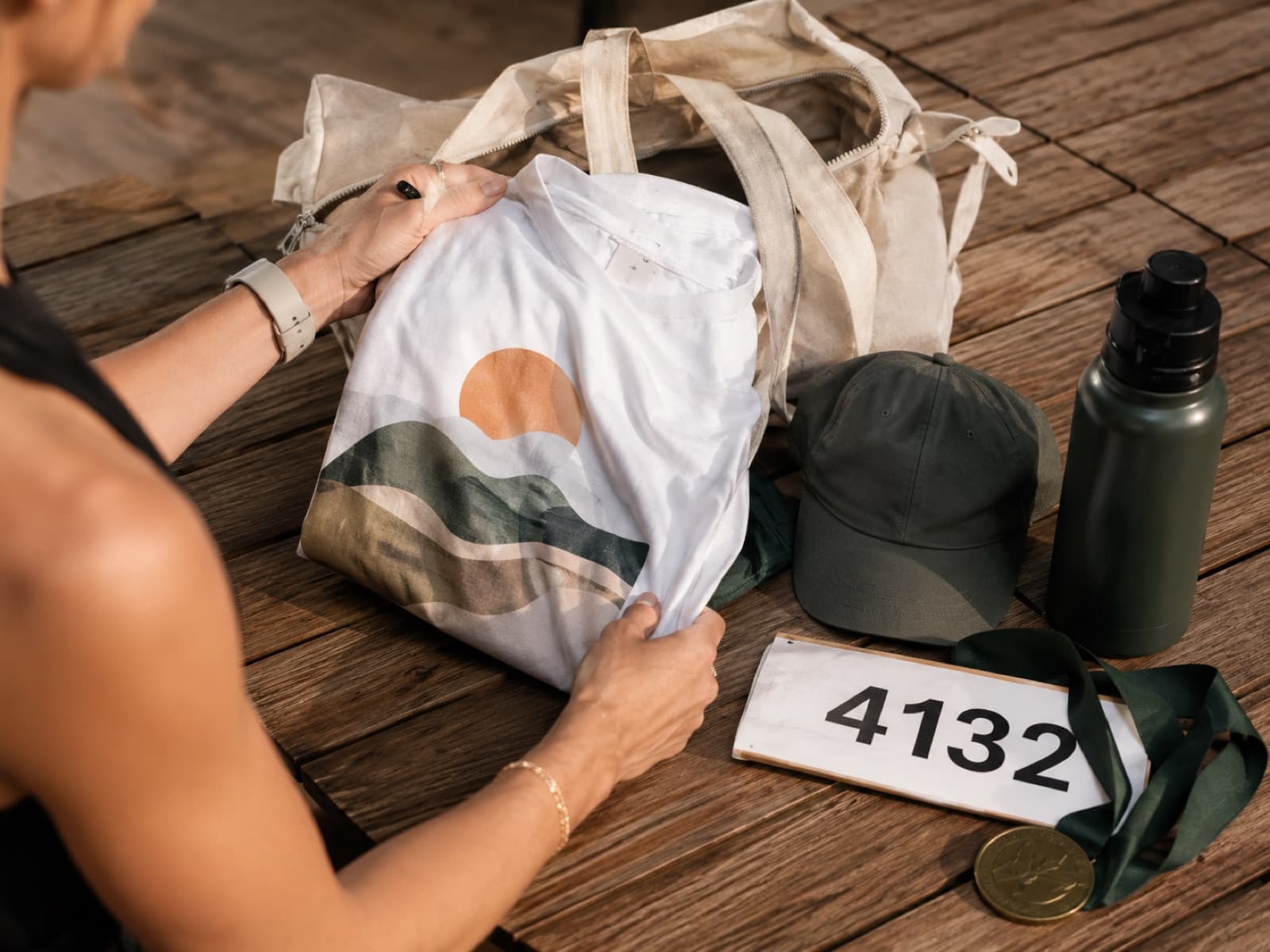 Custom race merch — a soft finisher tee, branded cap, and hydration bottle laid out before a marathon