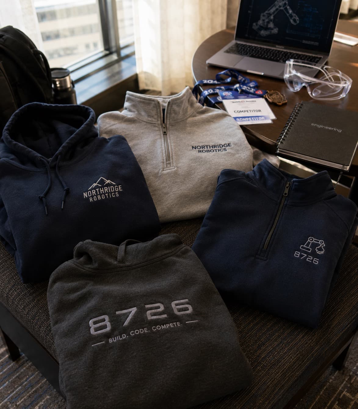 Custom club hoodies and quarter-zips laid out before a competition
